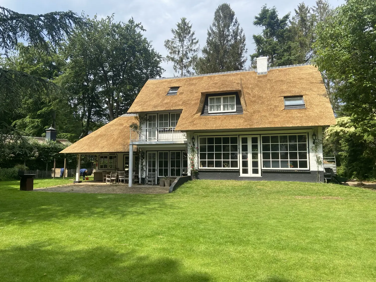 Villa met een nieuw rieten dak en dakkapellen, gezien vanaf het gazon