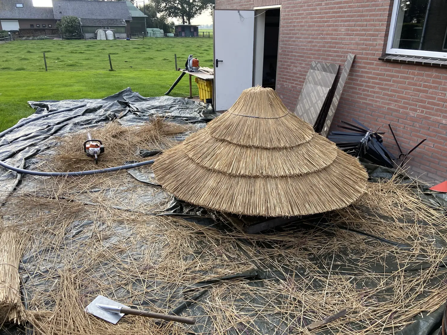 Rietdekker werkt aan een ronde rieten kap op de werkplek